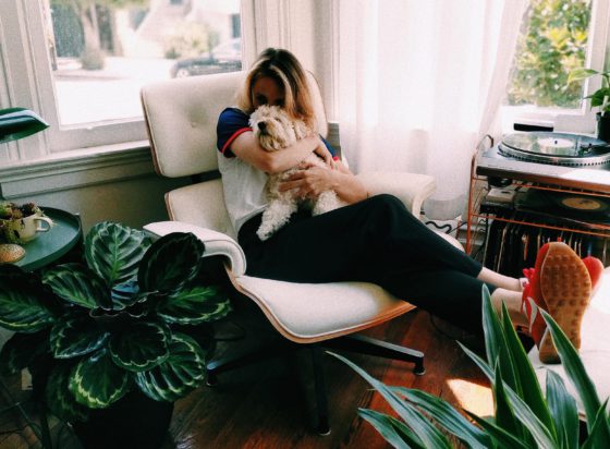 girl kissing dog on lounge chair surrounded by plants